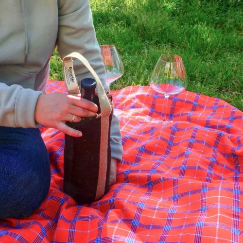une bouteille de vin dans une pochette isotherme sur une couverture de pique nique