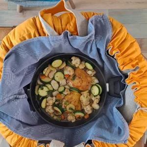 Réalisation client avec un kit Ecocotte : marmite norvégienne en tissu orange et bleu, utilisée pour cuisiner une recette de poulet aux légumes en cuisson douce sans énergie.