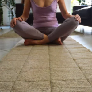 Personne assise en méditation sur un tapis en laine naturelle