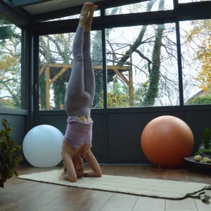 Personne en posture d’équilibre inversée sur un tapis de yoga en laine