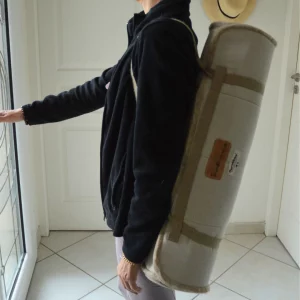 Tapis de yoga en laine transporté sur l’épaule grâce à une sangle en lin